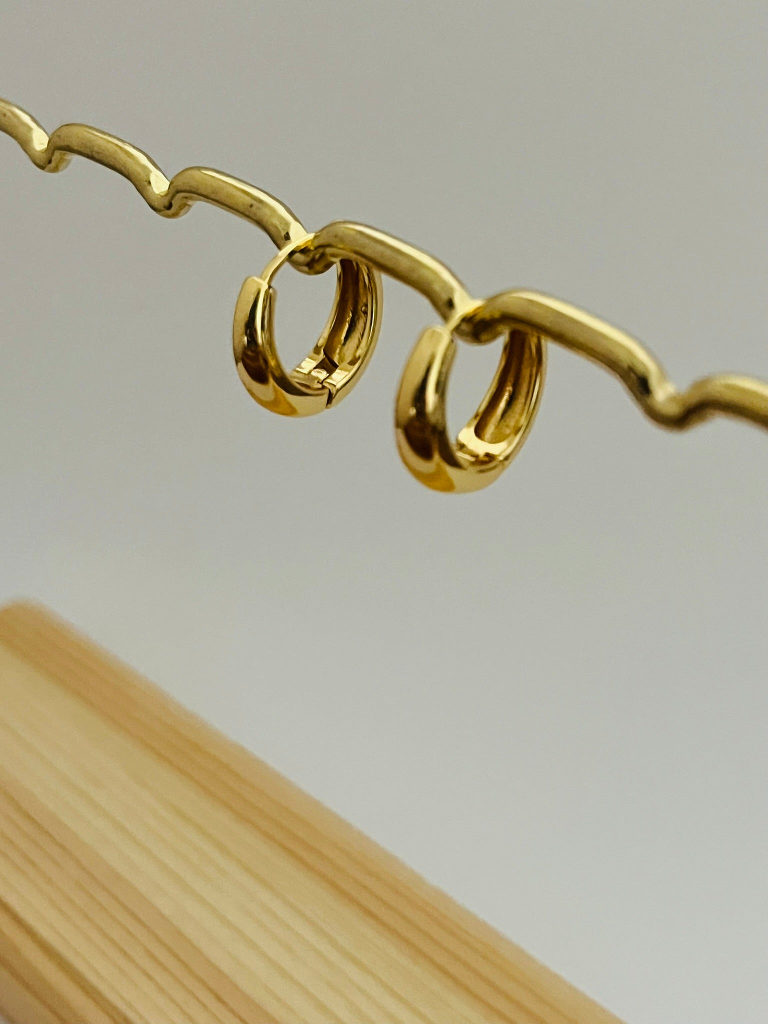 Gold huggie hoop earrings on a display