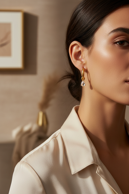 Woman wearing Lydia gold hoop earrings with teardrop crystal pendant, lifestyle editorial shot