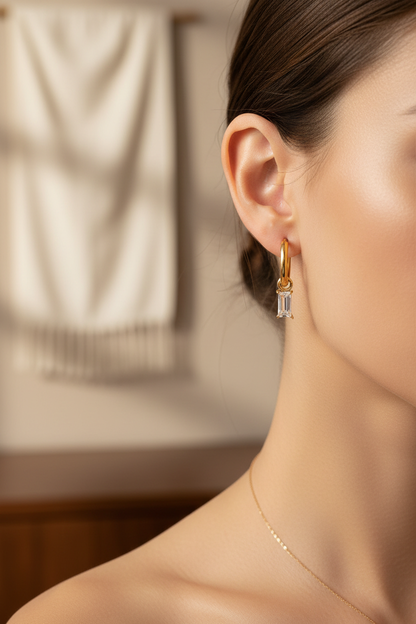Woman wearing Lydia gold hoop earrings with rectangular baguette crystal pendant, lifestyle editorial shot